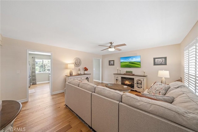 29251 Pebble Beach Dr, Menifee, CA 92586 - living area with ceiling fan, baseboards, a glass covered fireplace, and light wood-type flooring
