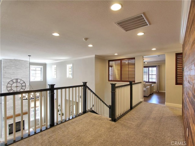 hall featuring ornamental molding, visible vents, and an upstairs landing