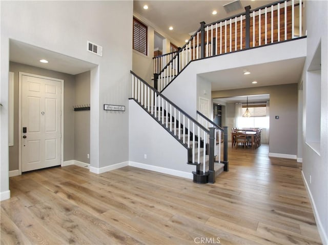 entrance foyer featuring visible vents, baseboards, a high ceiling, stairway, and wood finished floors