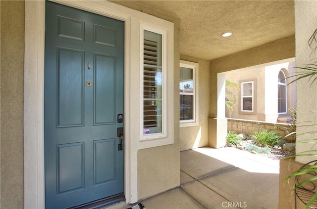 doorway to property with a porch and stucco siding