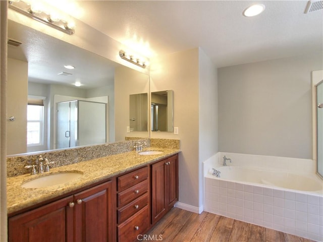 bathroom featuring a sink, visible vents, wood finished floors, and a garden tub