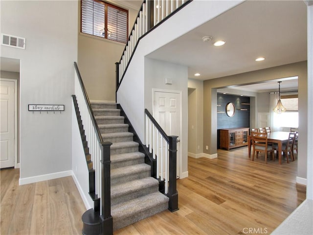 stairway featuring wood finished floors, baseboards, visible vents, and recessed lighting