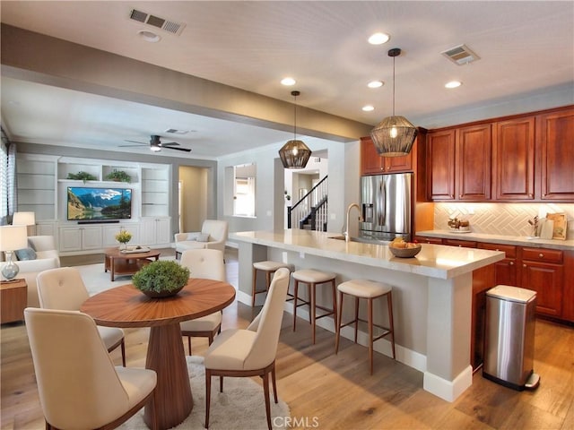 kitchen featuring stainless steel fridge with ice dispenser, open floor plan, visible vents, and light countertops