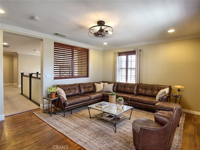 living room featuring visible vents, baseboards, ornamental molding, a chandelier, and wood finished floors