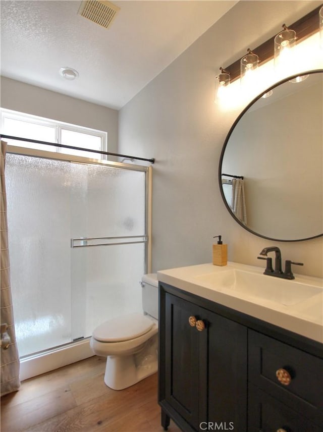 full bathroom with visible vents, toilet, wood finished floors, a baseboard heating unit, and a stall shower