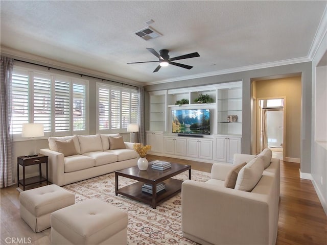 living area featuring visible vents, a ceiling fan, a textured ceiling, crown molding, and light wood finished floors