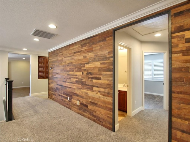 hall with wooden walls, visible vents, light colored carpet, and crown molding
