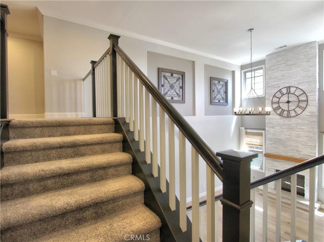 staircase featuring ornamental molding, visible vents, wood finished floors, a notable chandelier, and baseboards