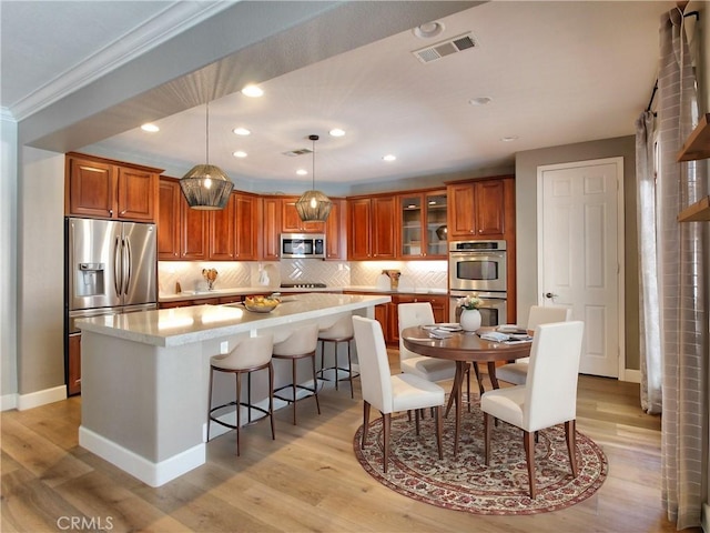 kitchen with visible vents, light countertops, brown cabinets, light wood finished floors, and stainless steel appliances