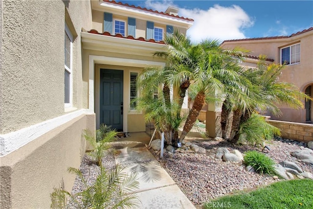 entrance to property with a tile roof and stucco siding