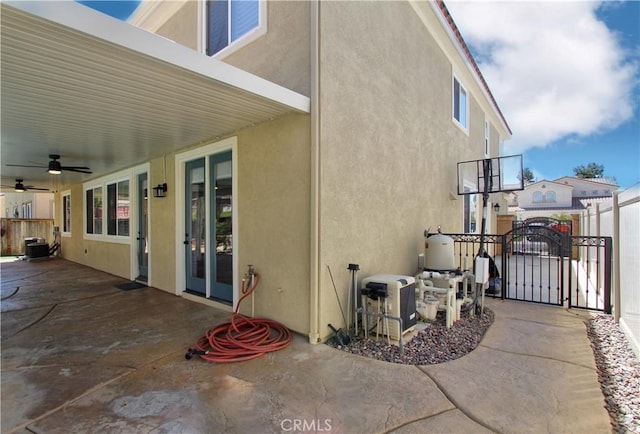 exterior space with fence, a gate, and a ceiling fan