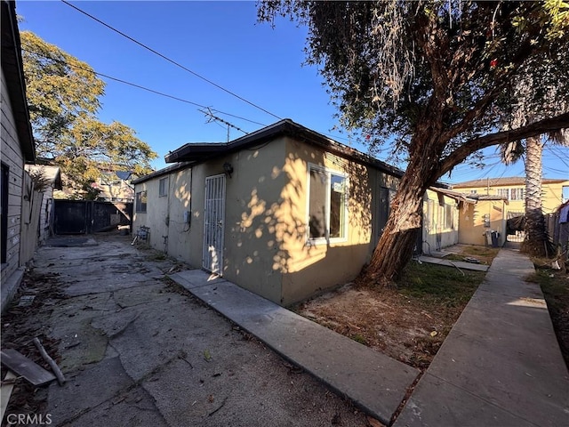 view of side of property featuring fence and stucco siding