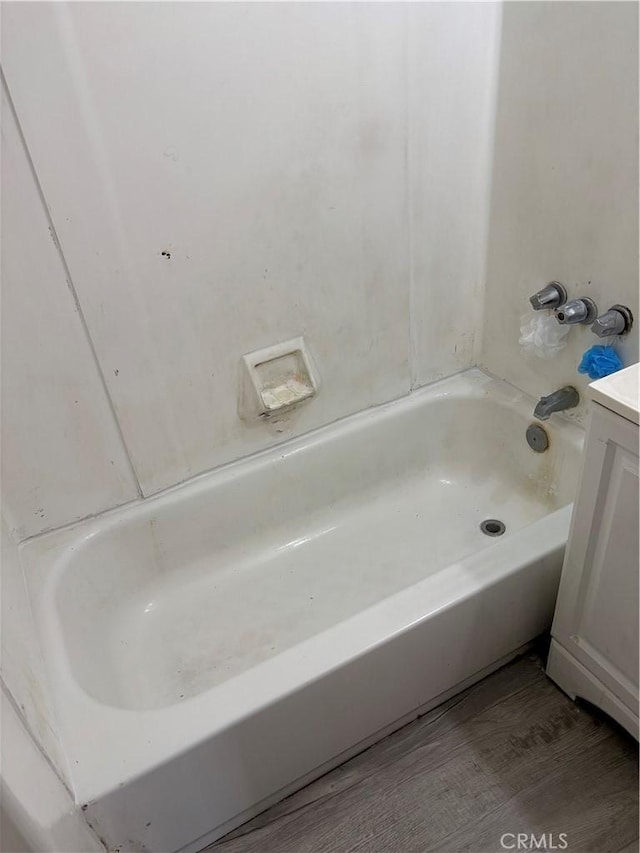 bathroom featuring vanity, a bath, and wood finished floors
