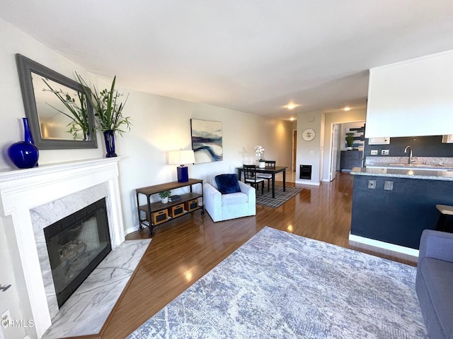 living area with baseboards, wood finished floors, and a high end fireplace