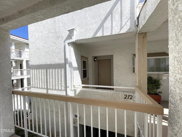 view of exterior entry featuring stucco siding and a balcony
