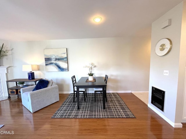 dining area with a fireplace, baseboards, heating unit, and wood finished floors