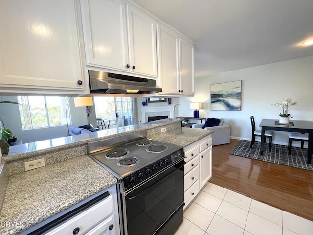 kitchen featuring light tile patterned floors, electric range, white cabinets, under cabinet range hood, and open floor plan
