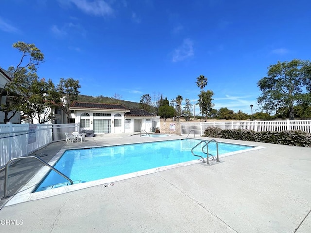 pool with a patio area and fence