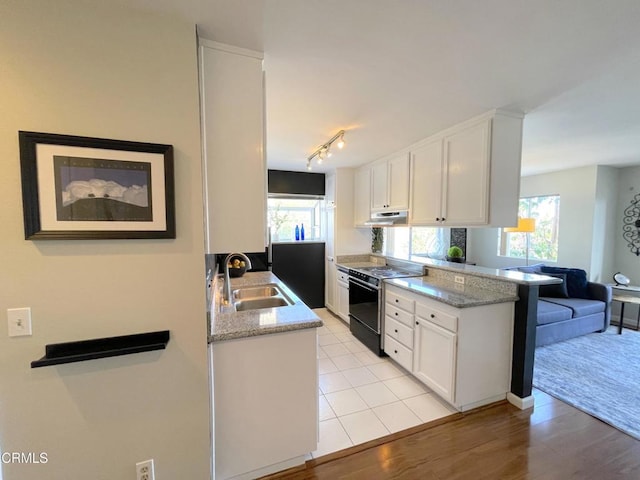 kitchen featuring a peninsula, black electric range oven, under cabinet range hood, white cabinets, and a sink