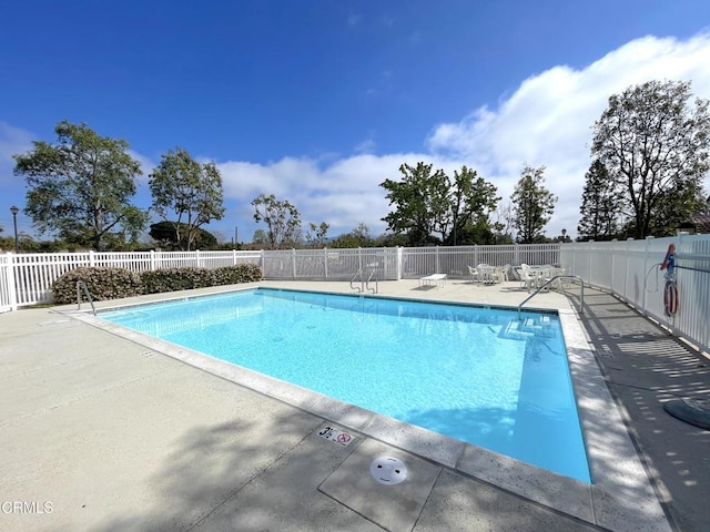 community pool with a patio area and fence