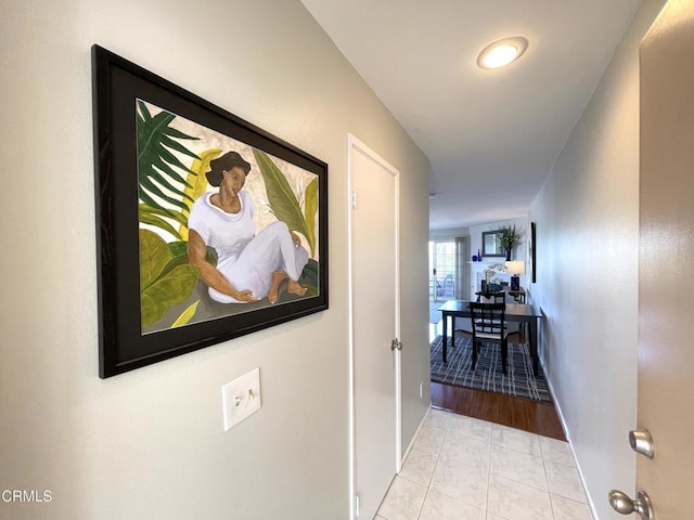 hallway with tile patterned floors and baseboards