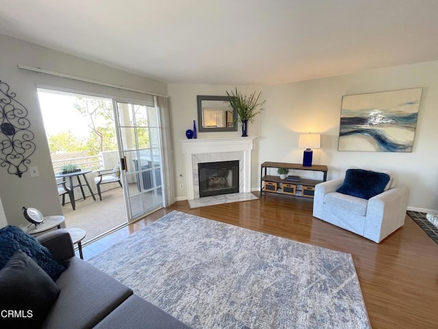 living room featuring wood finished floors, a high end fireplace, and baseboards