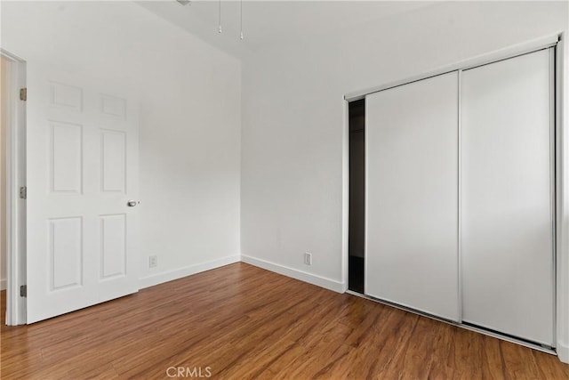unfurnished bedroom with a closet, baseboards, and wood finished floors