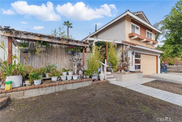 view of front of property with an attached garage, fence, driveway, and stucco siding