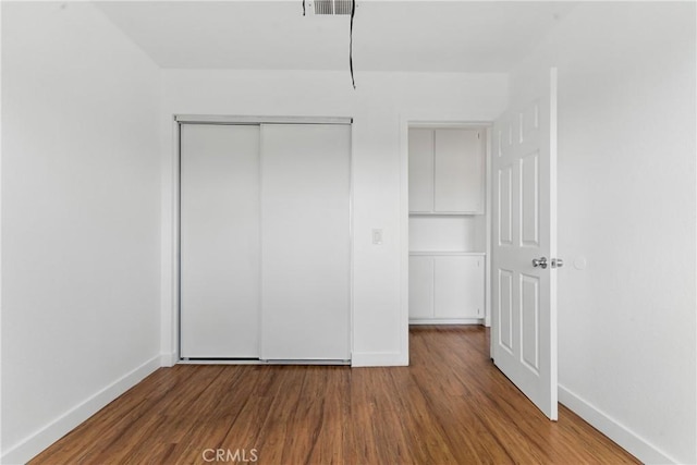 unfurnished bedroom with a closet, baseboards, and wood finished floors