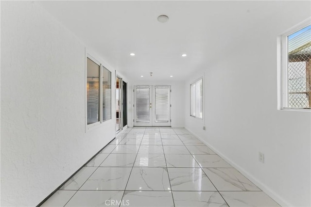 hallway with baseboards, recessed lighting, and marble finish floor