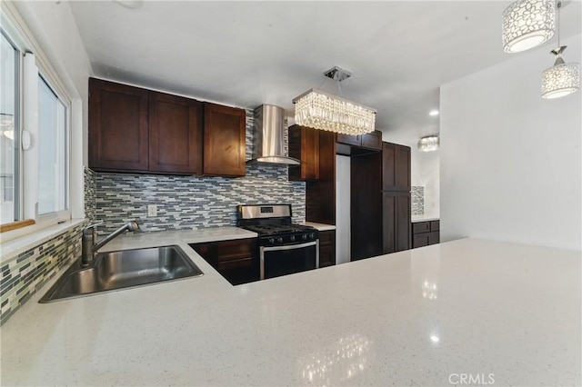 kitchen with a sink, wall chimney range hood, decorative backsplash, and stainless steel range with gas cooktop
