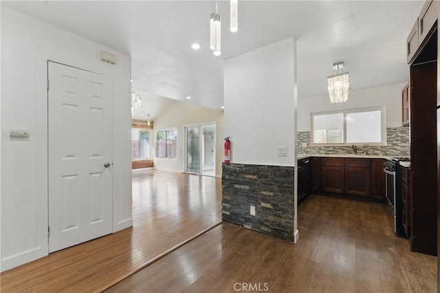 interior space with stainless steel gas range, a sink, dark wood-style floors, and an inviting chandelier