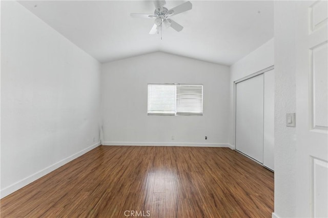 unfurnished bedroom featuring a closet, baseboards, a ceiling fan, wood finished floors, and lofted ceiling
