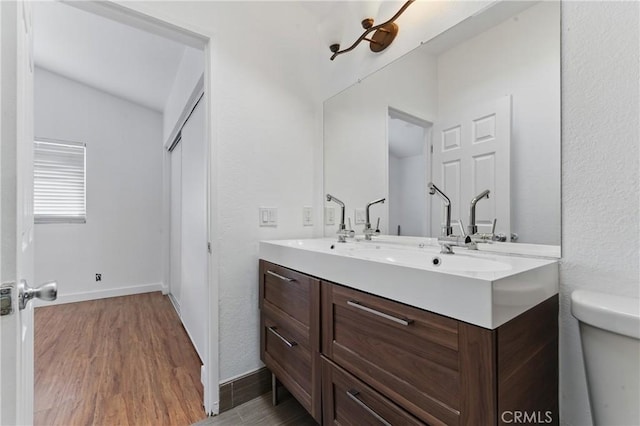 bathroom featuring toilet, vanity, wood finished floors, and baseboards