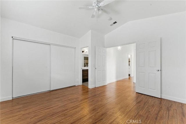 unfurnished bedroom featuring visible vents, baseboards, a closet, wood finished floors, and lofted ceiling
