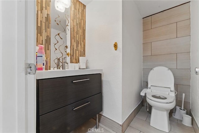 half bathroom with toilet, vanity, and baseboards
