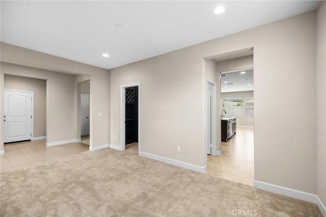 interior space with light carpet, a sink, baseboards, a spacious closet, and recessed lighting