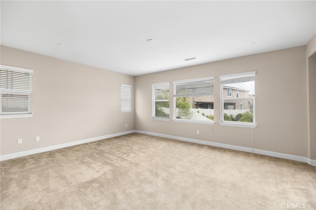 empty room featuring visible vents, light carpet, and baseboards