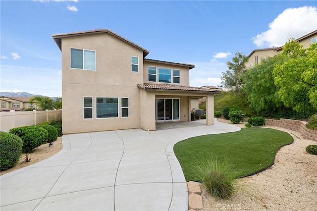 rear view of house featuring fence, a patio area, a tile roof, and stucco siding