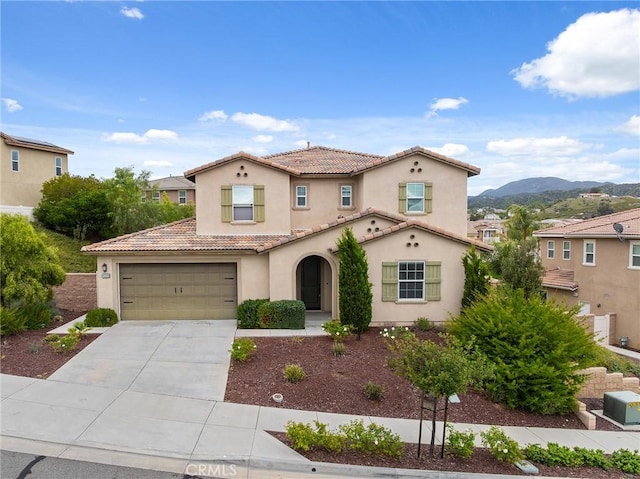 mediterranean / spanish home featuring driveway, a tiled roof, a mountain view, a garage, and stucco siding