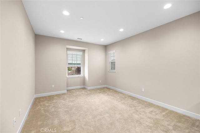 spare room featuring baseboards, light carpet, and recessed lighting