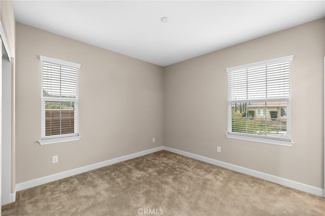 spare room featuring carpet and baseboards