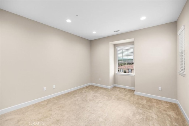spare room featuring recessed lighting, light carpet, visible vents, and baseboards