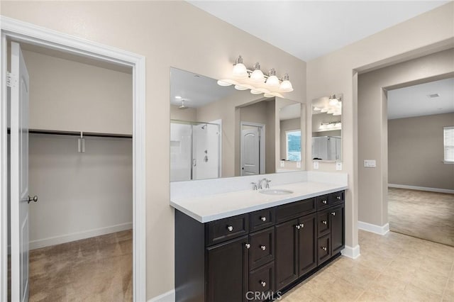 bathroom with plenty of natural light, a spacious closet, vanity, baseboards, and walk in shower