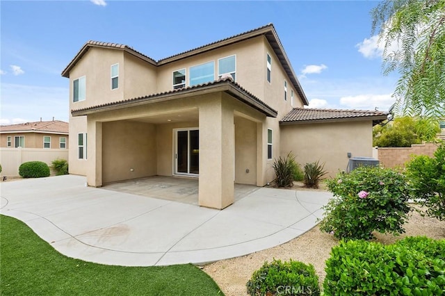 back of house featuring stucco siding, a tile roof, fence, and a patio