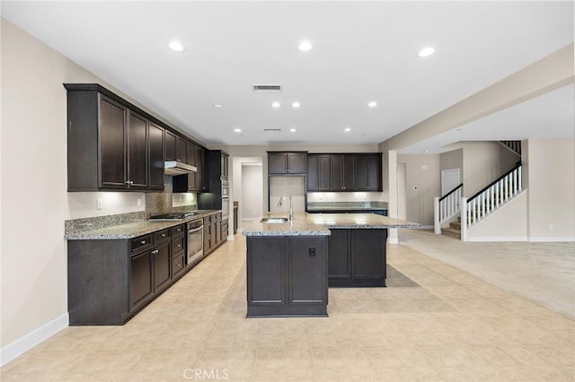 45600 Gresham, Temecula, CA 92592 - kitchen with a sink, appliances with stainless steel finishes, baseboards, a center island with sink, and dark brown cabinetry