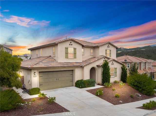 mediterranean / spanish-style house featuring stucco siding, a tile roof, driveway, and a garage