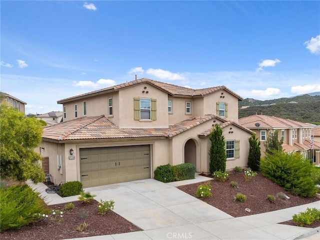 mediterranean / spanish house with a tiled roof, driveway, and stucco siding