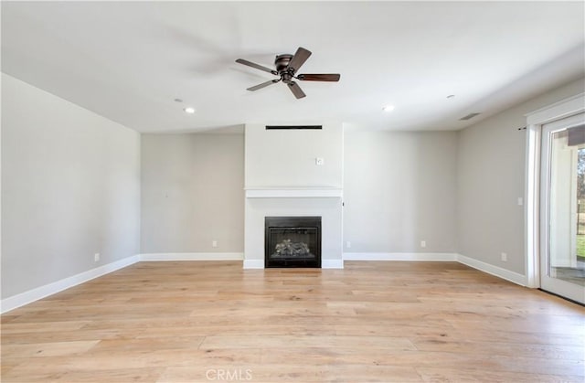 unfurnished living room featuring a glass covered fireplace, light wood finished floors, baseboards, and ceiling fan