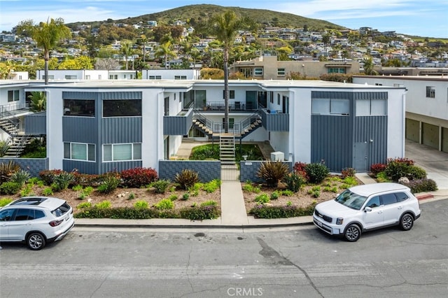 view of property with stairway, a mountain view, a fenced front yard, and a residential view